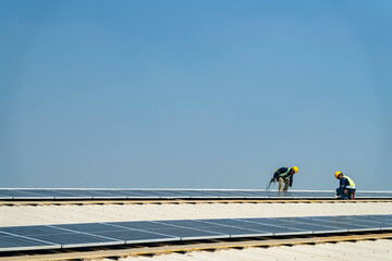 Wall Mural - two engineers install solar panels on a rooftop, wearing safety gear and helmets. the scene showcase