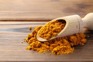 Sticker - Turmeric powder in scoop on wooden table, closeup. Space for text