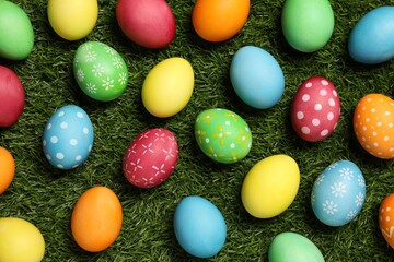 Wall Mural - Beautiful decorated Easter eggs on green grass, flat lay