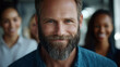 © VALUEINVESTOR - A happy bearded man with business people smiling in the background, generative AI