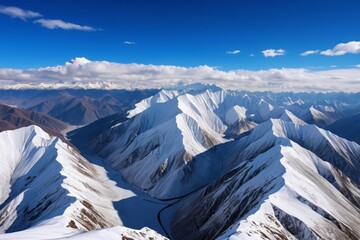 Wall Mural - mountains covered in snow and clouds with a winding road in the middle