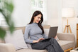© NAMPIX - Beautiful woman sit on couch working on laptop browsing internet at home