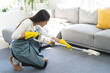 © KMPZZZ - Vacuuming cleaning, housekeeping asian young woman, girl cleanup with portable cordless vacuum cleaner to clean floor on rug in living room at home, house. Housework or household and chores concept.