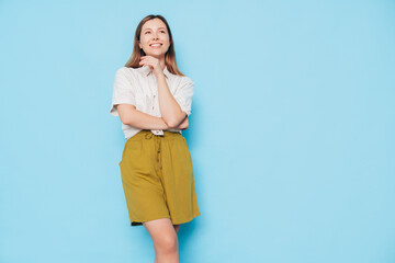 Sticker - Young beautiful smiling brunette female in trendy summer  clothes. Carefree woman posing near blue wall in studio. Positive model. Cheerful and happy