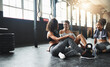 © Donson2000/peopleimages.com - Conversation, gym and women on floor, relax and goals with fitness, gossip and exercise. Happy people, friends and wellness facility for training, resting and discussion for progress and support