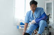 © Phimwilai - Patient wearing arm sling and leg brace sitting on wheelchair in hospital room