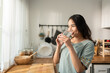 © Kawee - Asian young attractive woman drink a glass of water in kitchen at home.
