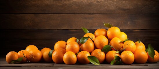Poster - Vibrant pile of fresh oranges with green leaves on a rustic wooden table against a dark wood background creating ample copy space for text
