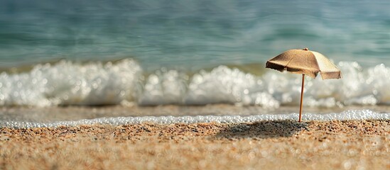 Aufkleber - Minimalist beach scene featuring a small umbrella on golden sand with gentle waves in the background creating ample copy space for advertising.