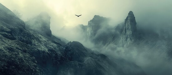 Aufkleber - Misty mountains at dawn with dramatic peaks shrouded in fog and a soaring bird in the sky, creating a serene and mysterious landscape.