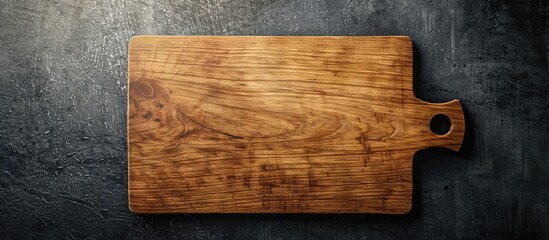 Aufkleber - Wooden rectangular cutting board on dark concrete surface with space for text, featuring warm brown tones and a rounded handle on the side.