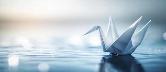 Leinwandbilder - Elegant origami crane positioned on calm shimmering water against a soft blurred background featuring cool blue and warm sunset tones.