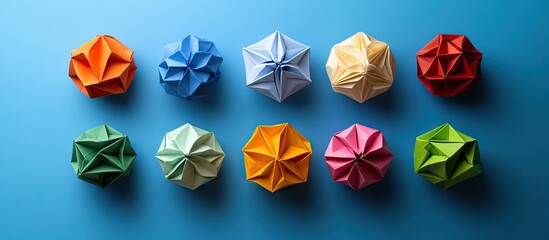 Poster - Colorful origami shapes arranged in two rows of five on a vibrant blue background with shades of red, green, yellow, orange, blue, and pink.