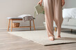 © Pixel-Shot - Woman in pajamas with book standing on carpet barefoot. Closeup