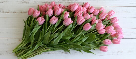 Aufkleber - Fresh pink tulips arranged elegantly on a white wooden surface from a top view with green leaves vibrant spring bouquet copy space available