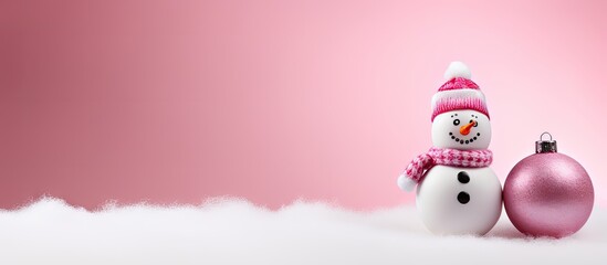 Poster - Decorative snowman with pink scarf and bauble on soft pink background with white snow, positioned right for copy space on the left side