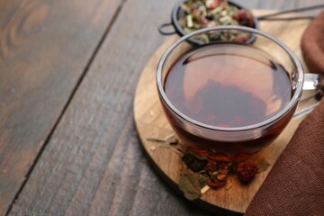 Wall Mural - Delicious herbal tea and dry leaves on wooden table, closeup. Space for text