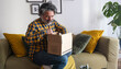 © Cavan - Happy man opening online shopping parcel at home