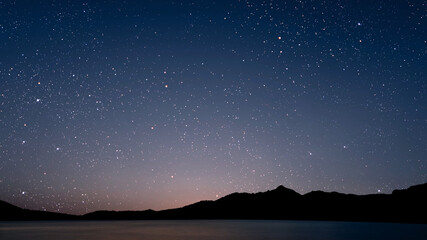 Wall Mural - A movement of stars in the night sky with the view of mountains..