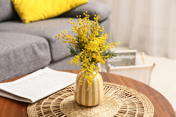 Canvas Print - Vase with mimosa flowers and newspaper on table in living room, closeup