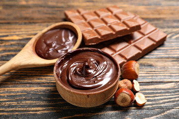 Canvas Print - Bowl and spoon of sweet chocolate spread with hazelnuts on wooden background