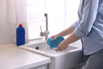 Wall Mural - Woman washing dishes in kitchen sink, closeup