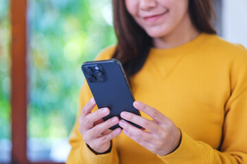 Wall Mural - Closeup image of a woman holding and using smart phone at home