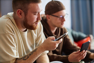 Wall Mural - Side view close up of bearded sports fan holding smartphone while checking game updates online, copy space