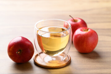 Wall Mural - Glass of apple cider and red apple fruit on wooden background