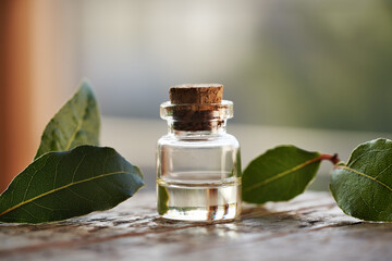 Wall Mural - A bottle of aromatherapy essential oil with fresh bay leaf on a table