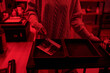 © Mediaphotos - Close up of young woman dipping developed photo print in chemical tray while working on analog prints in darkroom lit by red light copy space
