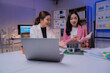 © Tj - Two asian real estate agents discussing a new house project with house model, laptop, documents and graphs, working together in the office at night