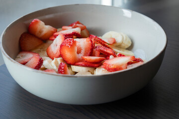 Wall Mural - white ceramic bowl full of strawberry and banana slices close-up