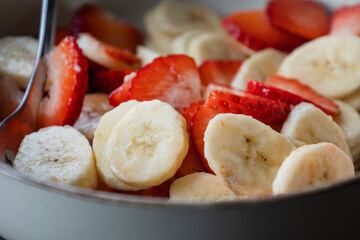 Wall Mural - white ceramic bowl full of strawberry and banana slices close-up