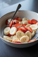 Wall Mural - white ceramic bowl full of strawberry and banana slices close-up