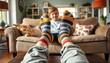 © Aliona - A person wearing colorful striped socks relaxes on a couch, while a child sits nearby, creating a warm atmosphere of comfort and family bonding. Ideal for lifestyle, family, and home content.