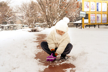 KId girl is makes snowballs with a snowball maker in the park. Freedom and happiness concept.