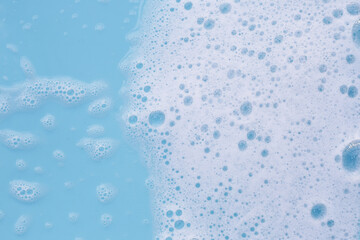 Wall Mural - Foam on blue background. Liquid soap bubbles