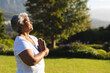 © wavebreak3 - Senior woman meditating outdoors in peaceful garden, enjoying morning sunlight, copy space