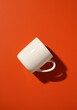 © Rohit k  - Minimalist white ceramic mug resting on vibrant orange surface, creating sharp shadow and bold color contrast, ideal for graphic design elements