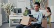 © ABCreative - Disabled ambitious man in shirt with Asian Korean beauty sits in wheelchair at desk in the company on knees holding cardboard box with packed things, gets fired from job unable to fulfill his duties