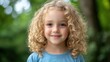 © SerPak - Smiling caucasian child with curly blond hair in blue shirt outdoors.