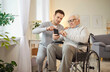 © Studio Romantic - Wheelchair senior man using smartphone app with kind medical brother, consultant nursing, health social care of elderly, doctor male geriatric nurse helping, healthcare hospital for old patient