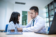 © SAHARAT - A male doctor is using a stethoscope to listen to a young girl's heartbeat during a health checkup and gives advice.