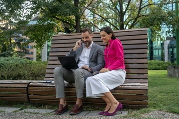 Wall Mural - Business colleagues using laptop outside of office building.