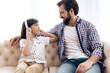 © Oleh Veres - Teenage boy in headphones listens to music, sitting with happy father on couch.