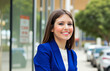 © Minerva Studio - Smiling businesswoman wearing blue suit standing in urban setting