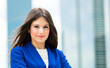 © Minerva Studio - Young businesswoman smiling with office buildings in background
