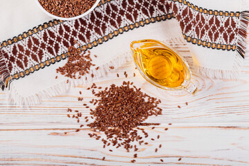 Wall Mural - Brown linen seeds, flaxseed vegetable oil on white rustic wooden background. Healthy super food top view, flat lay