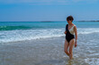 © JuanFrancisco - adult woman strolling along the beach enjoying the sea waves